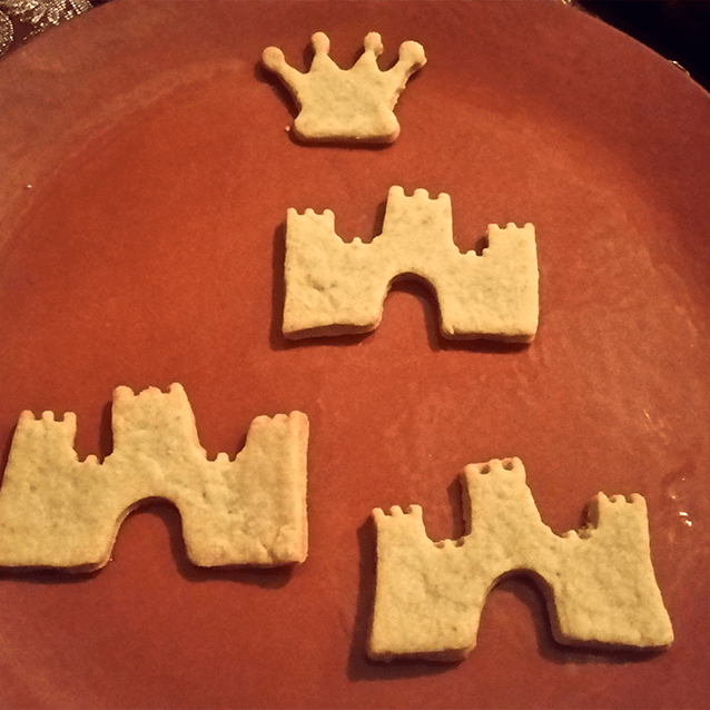 Kruunun- ja linnanmuotoisia keksejä punasavisella lautasella