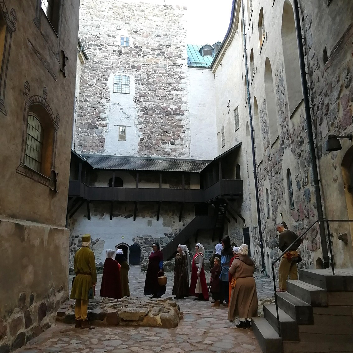 Ryhmä historiallisiin asuihin pukeutuneita harrastajia seisoo Turun linnan sisäpihalla