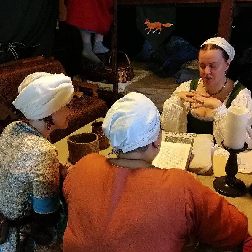 Kolme naisoletettua harrastajaa tutkii pöydän ääressä kirjoja